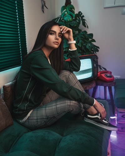 The woman is sitting beside the TV tufted sofa
